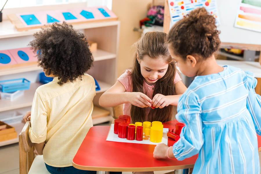 Children Playing Colorful Educational Game At Desk In Montessori
